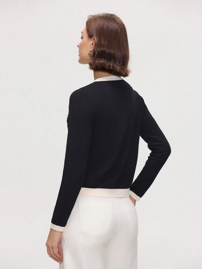 Woman wearing a black long-sleeve top with a white collar against a light gray background