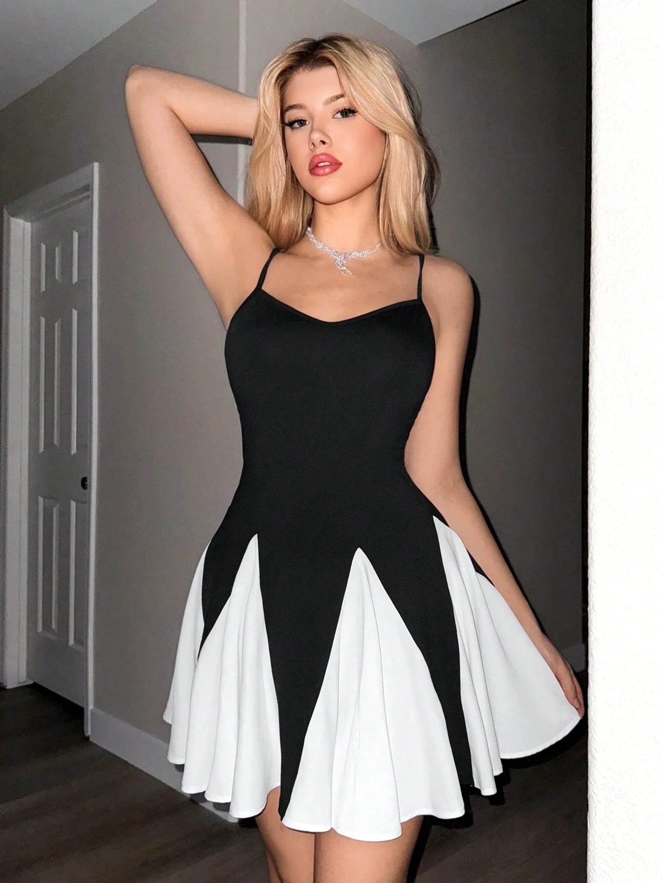 Woman wearing a black and white dress indoors.