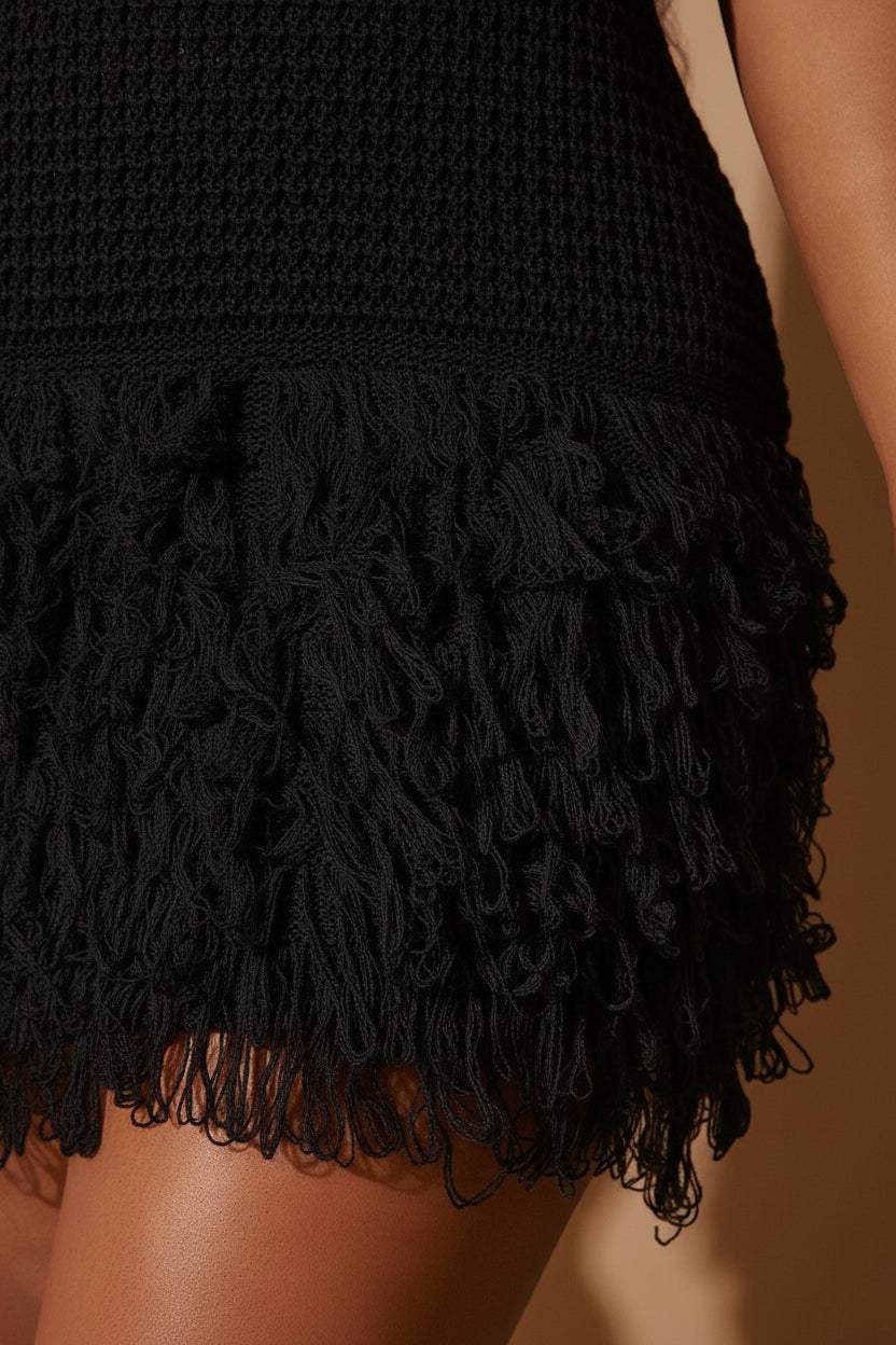 Close-up of a Black crochet top with white fringe details.