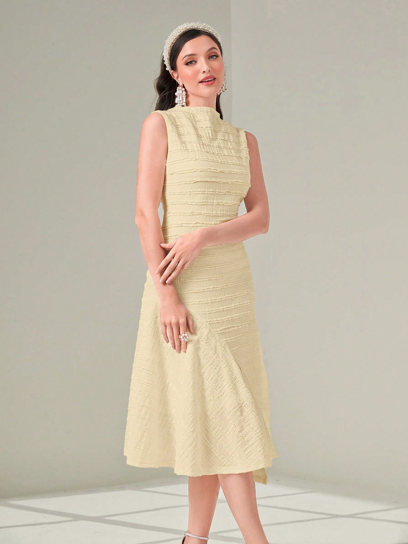 Woman wearing a light yellow dress with a textured pattern on a plain background