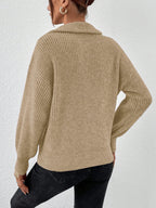 Person wearing a beige knitted sweater against a white background