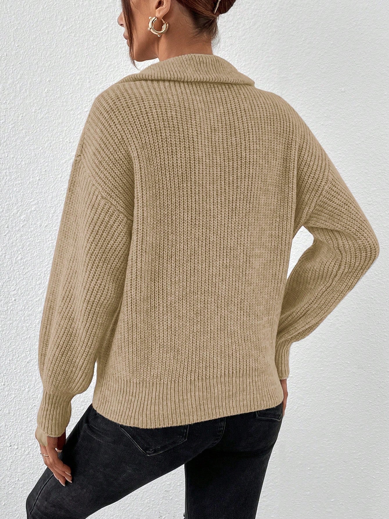 Person wearing a beige knitted sweater against a white background
