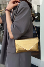 Person wearing a gray outfit with a gold handbag