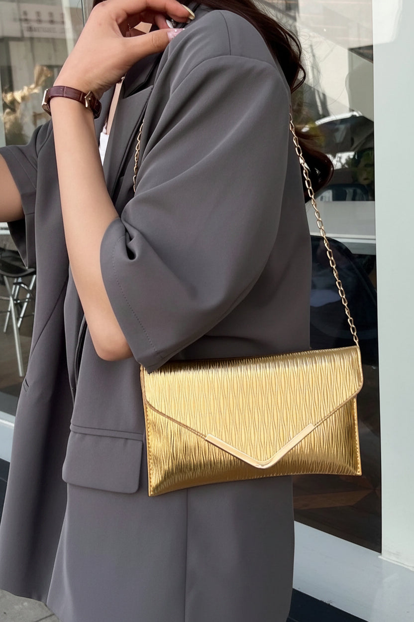 Person wearing a gray outfit with a gold handbag