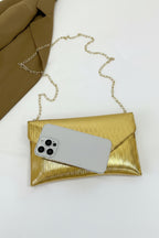 Gold clutch with a phone inside on a white background