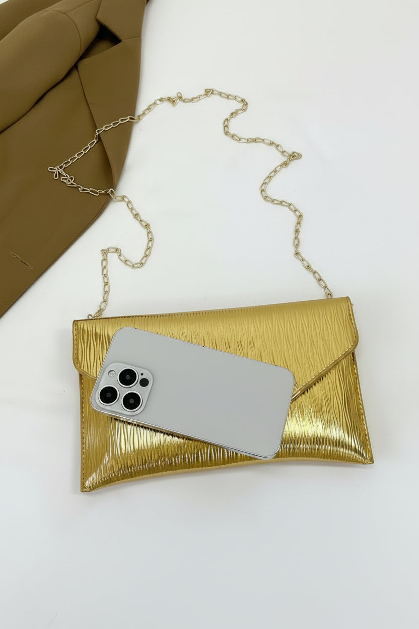 Gold clutch with a phone inside on a white background