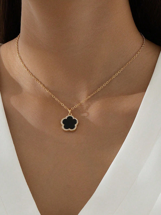 Gold necklace with a black clover pendant on a model wearing a white top.