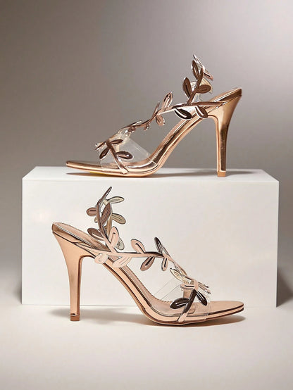 Rose gold high-heeled sandals with floral designs on a white platform against a gray background