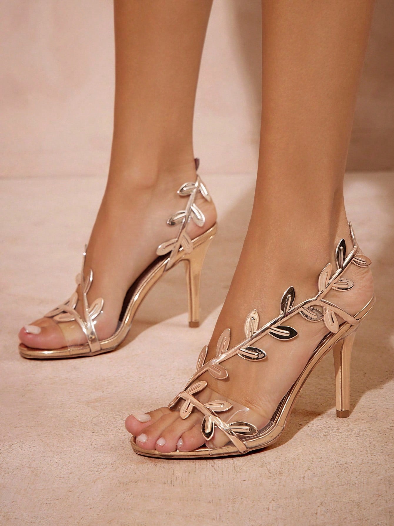 High-heeled sandals with leaf design on a neutral background