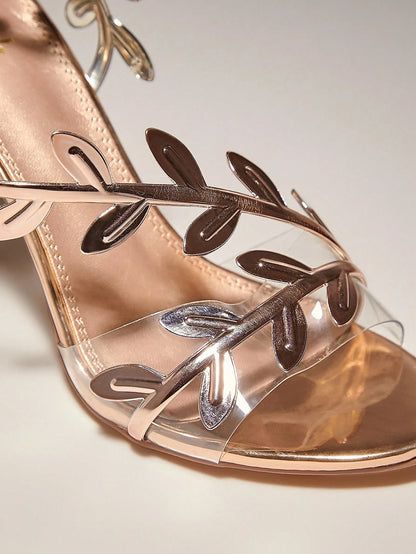 Rose gold sandal with leaf designs on a light background