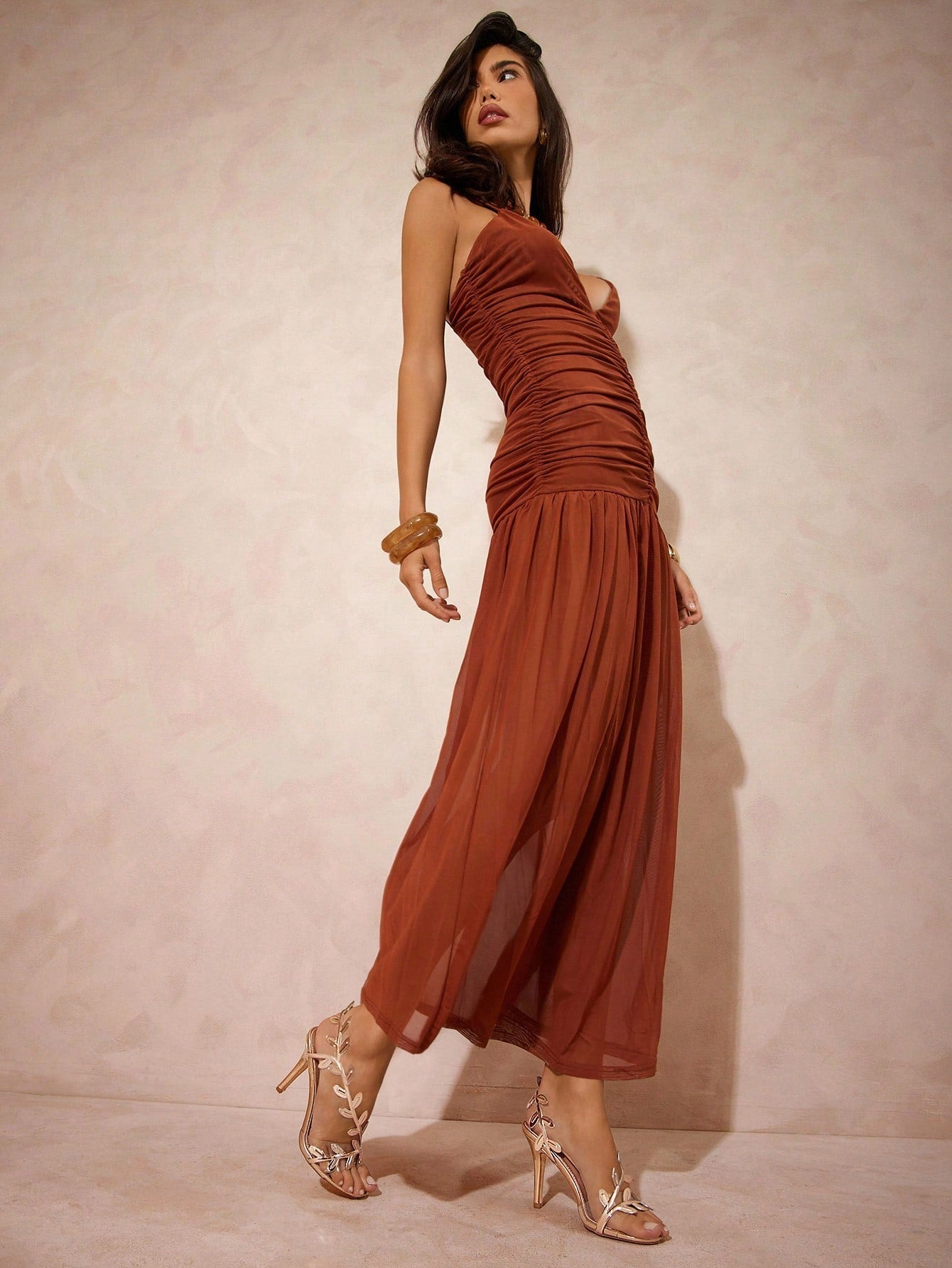 Woman wearing a rust-colored dress against a plain background