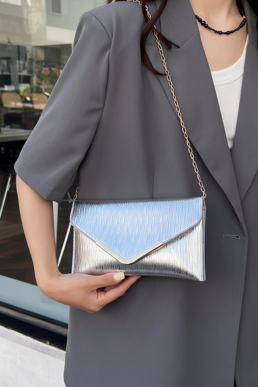 Person holding a silver and blue handbag with a blurred indoor background