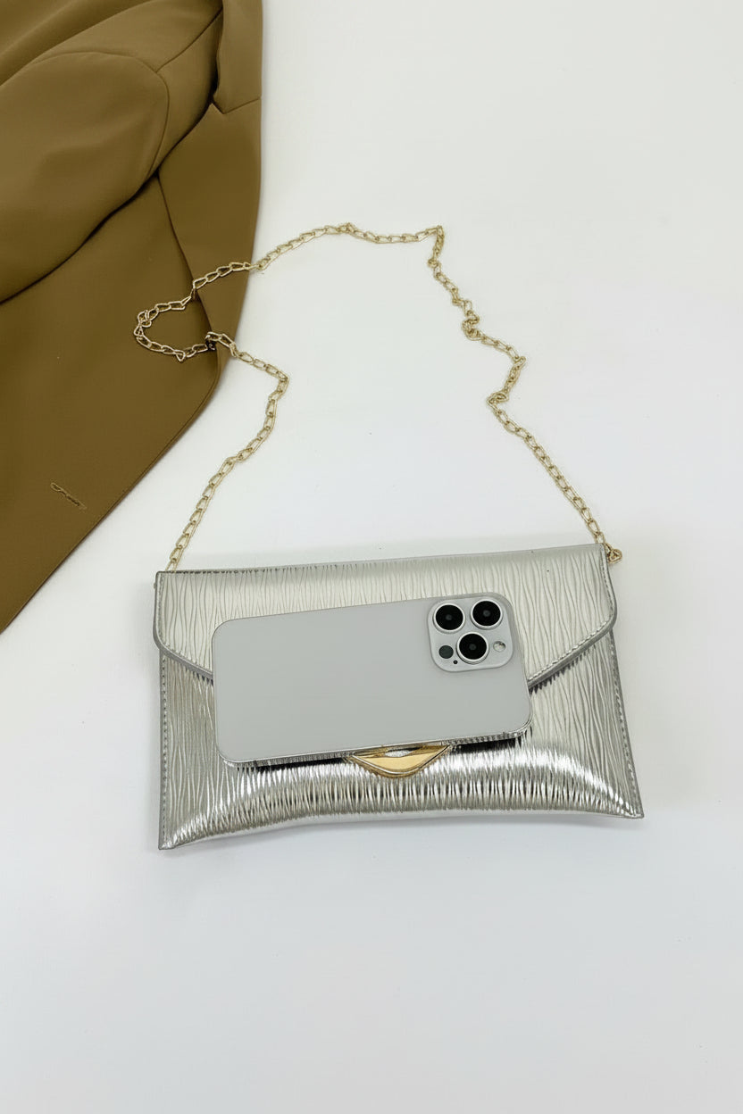 Silver clutch with gold chain on a white surface
