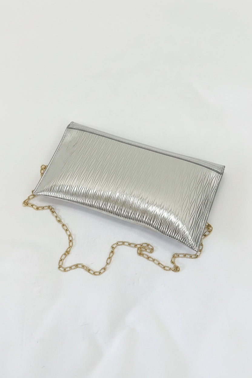Silver clutch bag with a gold chain on a white surface