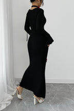 Person wearing a black dress standing against a white wall with a gray floor.