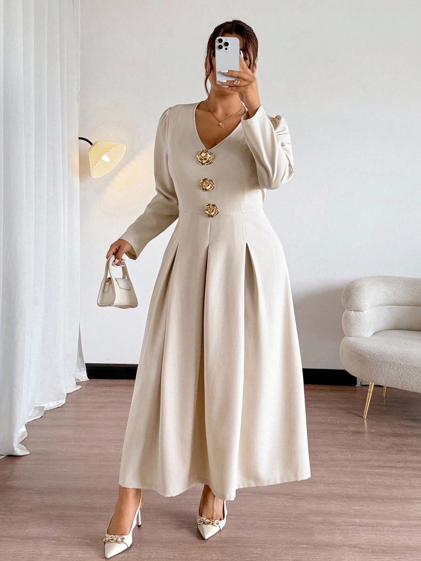 Woman wearing a long beige dress with gold buttons in a room.