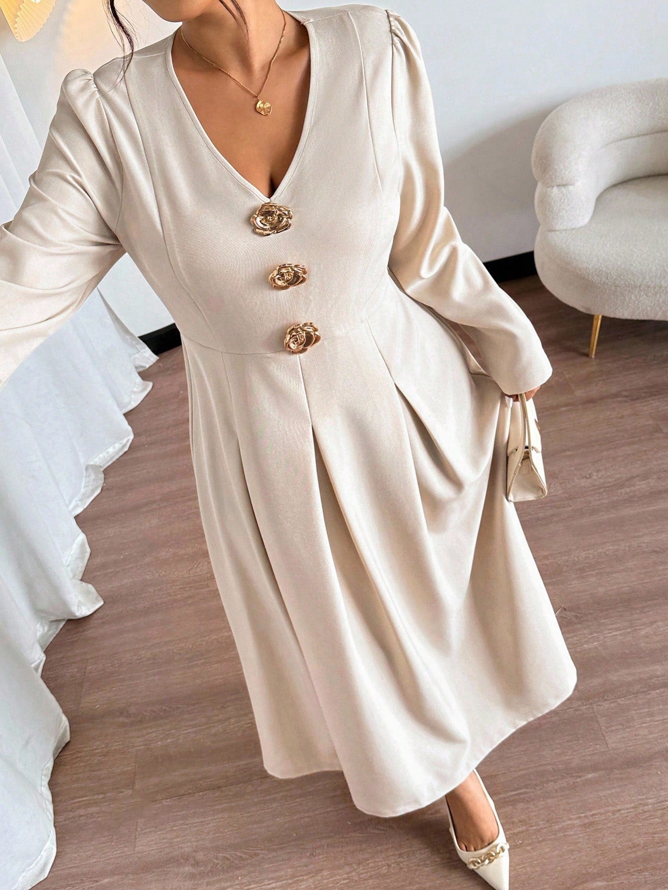 Woman wearing a beige dress with gold buttons in an indoor setting