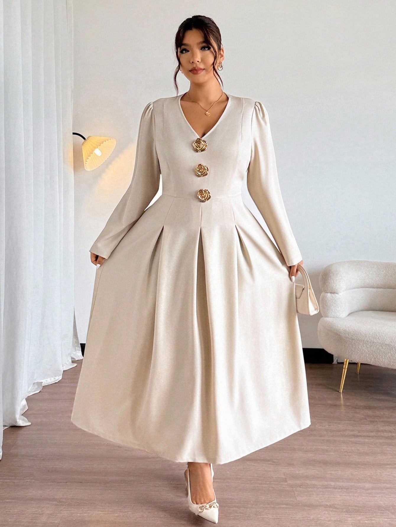 Woman wearing a beige dress with gold buttons in an indoor setting