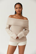 Beige off-shoulder sweater worn by a person on a plain background