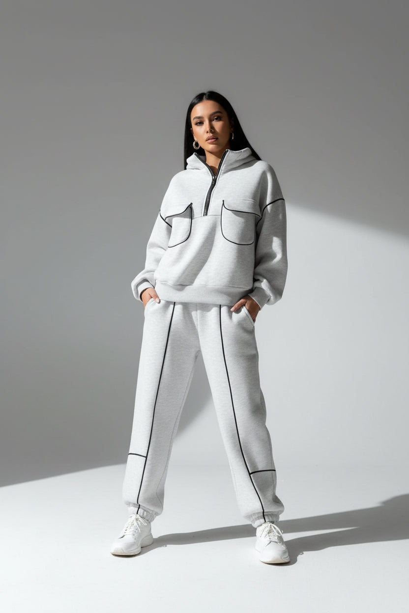 Person wearing a gray tracksuit with black accents in an urban setting