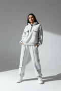 Person wearing a gray tracksuit with black accents in an urban setting
