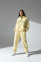 Person wearing a light yellow tracksuit on a gray background