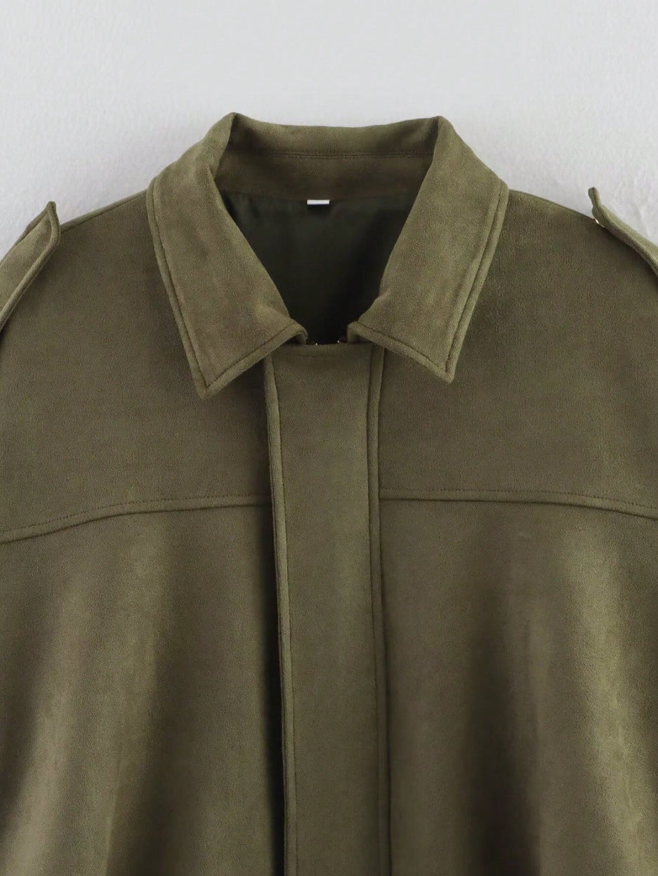 Close-up of a green suede jacket with a plain background