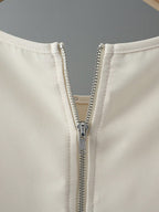 Close-up of a beige jacket with a silver zipper on a gray background