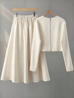 White long-sleeve top and skirt set on hangers against a gray background