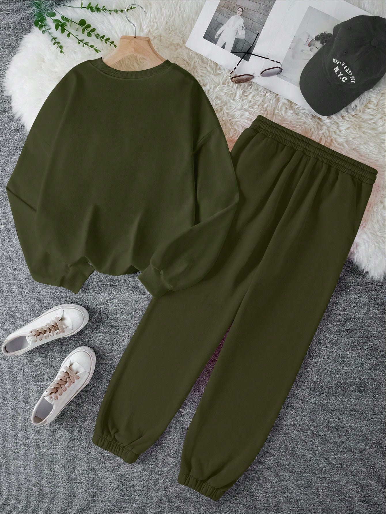 Green sweatshirt and pants set with white sneakers on a gray surface.
