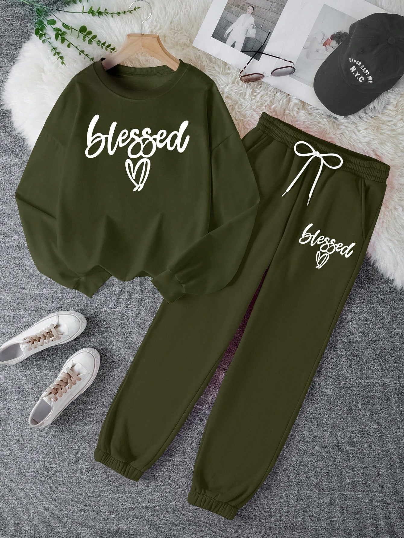 Green sweatshirt and pants set with 'blessed' text on a gray surface.