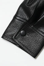 Close-up of a black leather jacket with a button on a white background