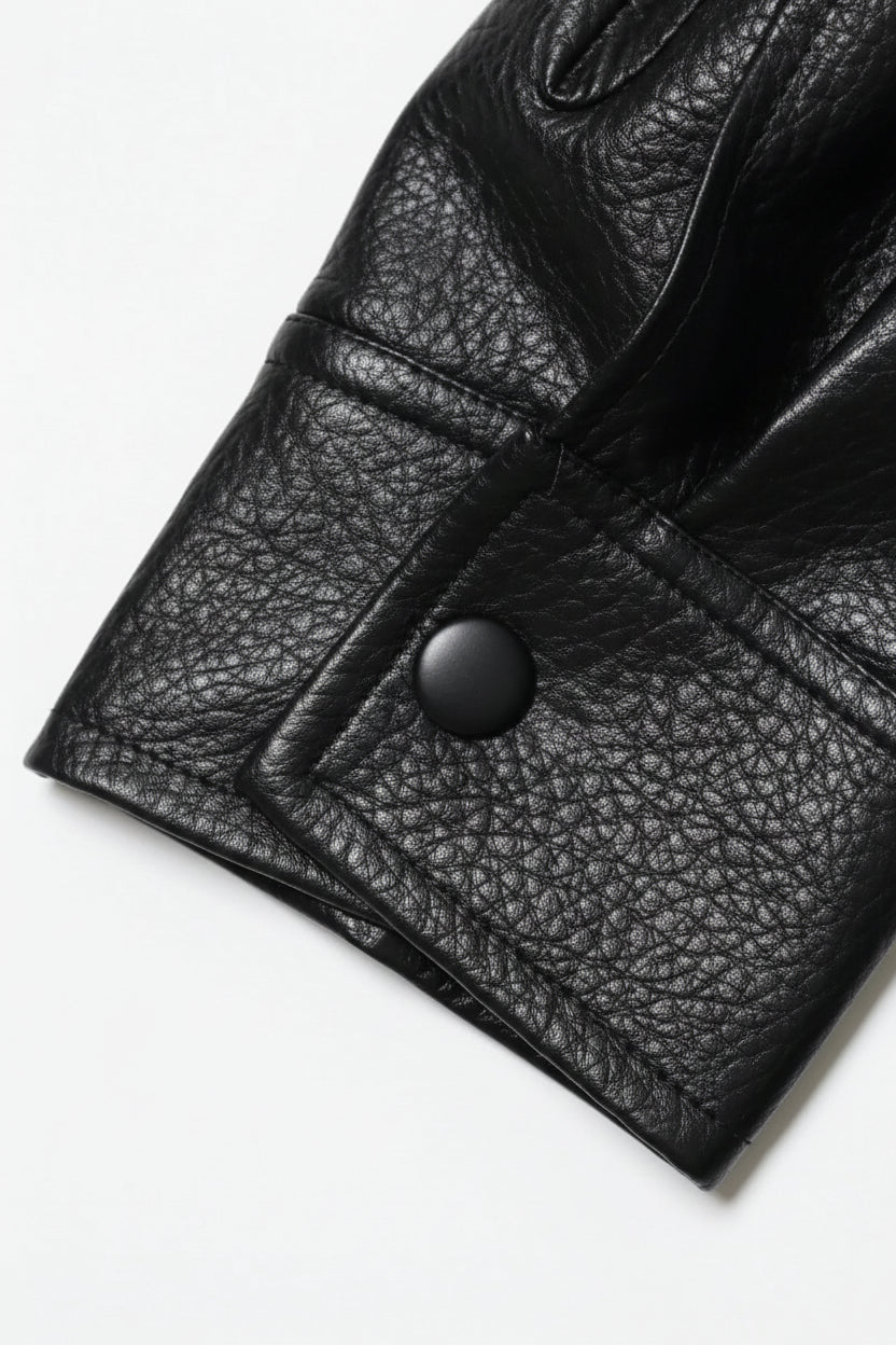 Close-up of a black leather jacket with a button on a white background