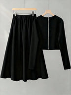 Black long-sleeve top and skirt set on hangers against a gray background