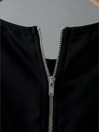 Close-up of a black garment with a silver zipper on a gray background