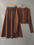 Brown long-sleeve top and skirt set on hangers against a gray background