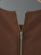 Close-up of a brown jacket with a silver zipper on a gray background