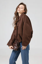 Woman wearing a brown oversized jacket on a plain background