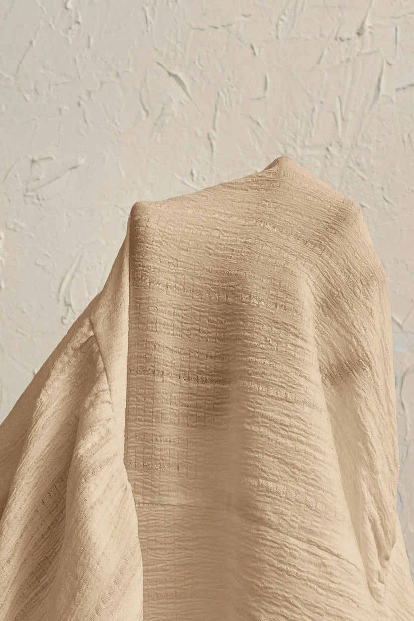 Beige fabric with textured pattern against a textured beige background