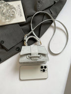 Small gray handbag on a smartphone with a magazine and fabric background