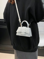 Person wearing a black outfit with a white textured handbag on a neutral background