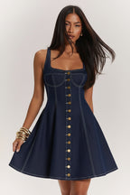 Woman wearing a blue denim dress with button details on a white background