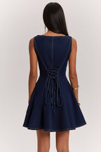 Woman wearing a navy blue dress with a tied waist on a white background