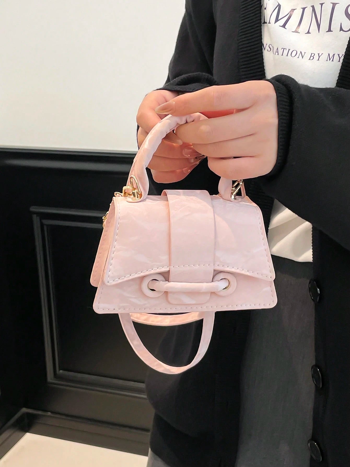 Person holding a small pink handbag with a plain background