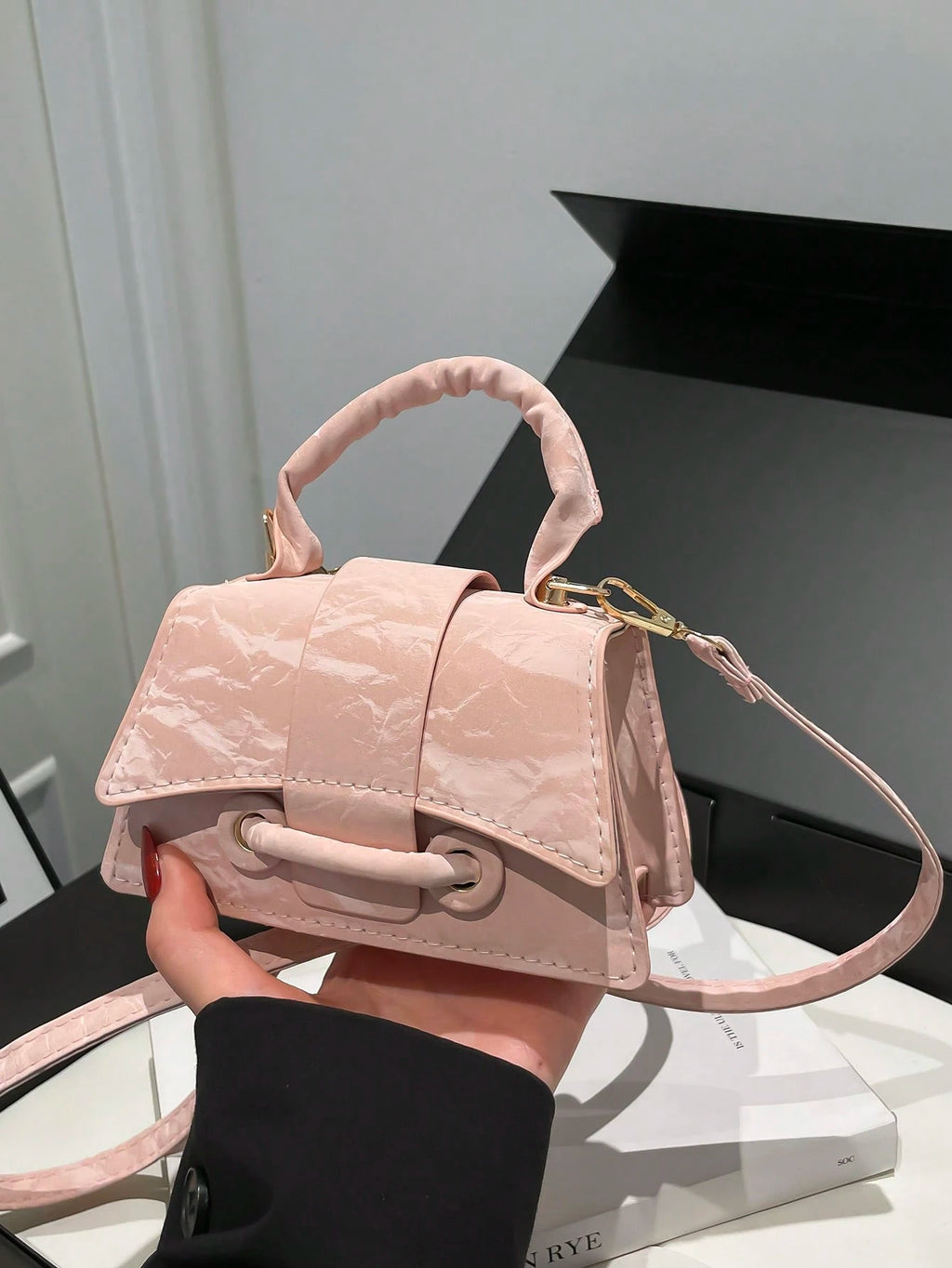 Pink handbag held by a person against a neutral background