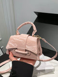Pink handbag held by a person against a neutral background