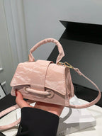 Pink handbag held by a person against a neutral background