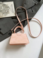 Pink handbag on a white surface with a magazine and gray fabric in the background