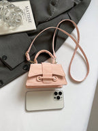 Small pink handbag with a phone on a white surface