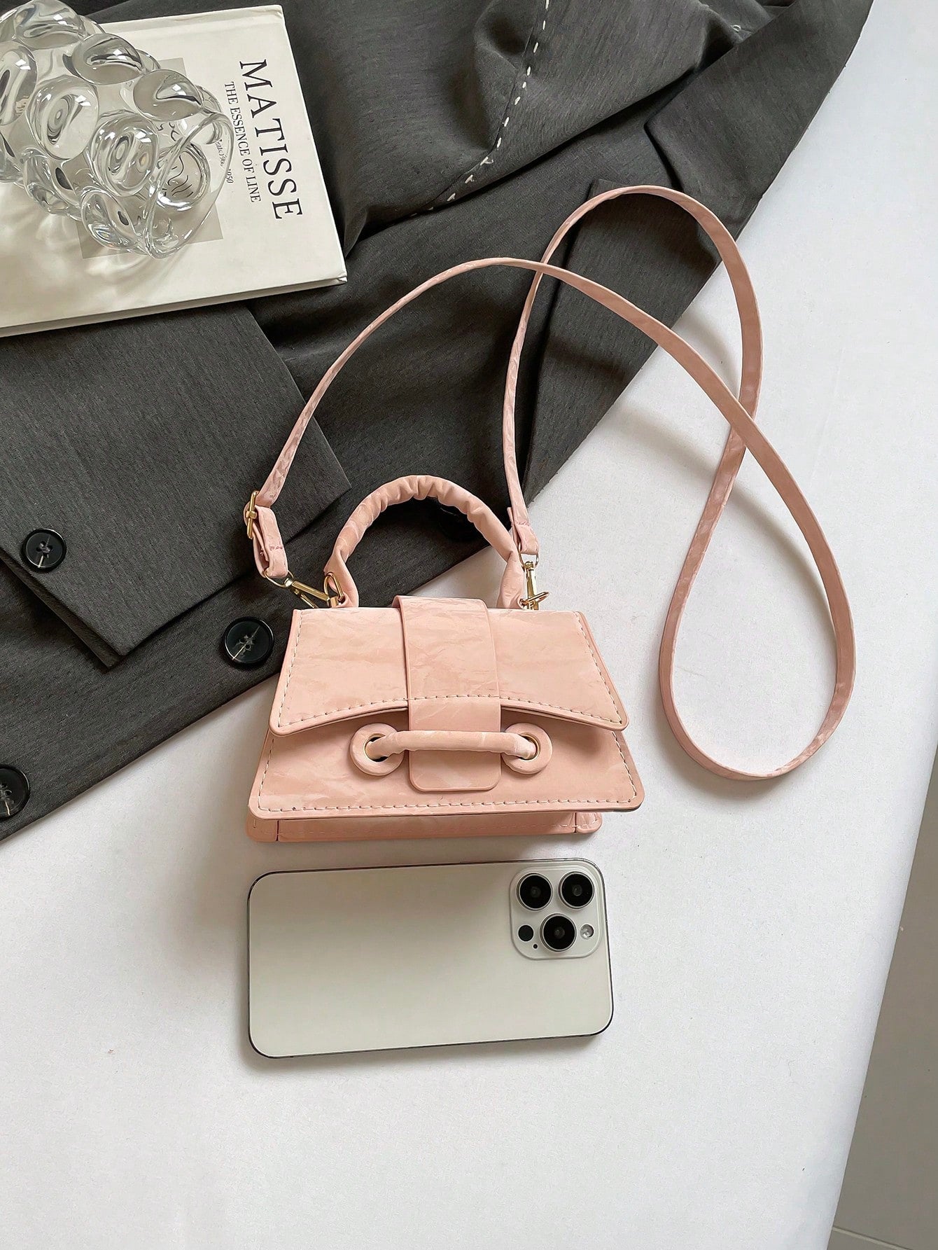 Small pink handbag with a phone on a white surface